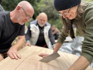 Ein Team aus drei Teilnehmern arbeitet mit Säge an einem Holzstück auf einer Bildungsreise in Japan.
