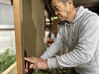 Yamamoto-Sensei arbeitet sorgfältig an der Kante der Putzwand, eine stille Demonstration seines Könnens mit der „Kelle“.